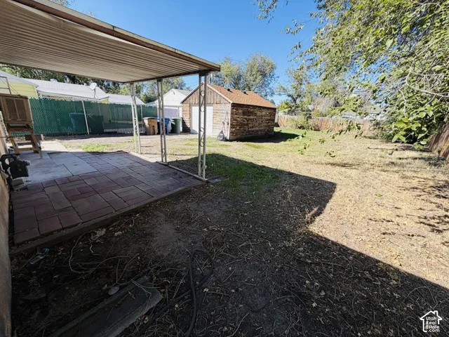 Patio with a metal awning, paver flooring, spacious yard, and a detached shed