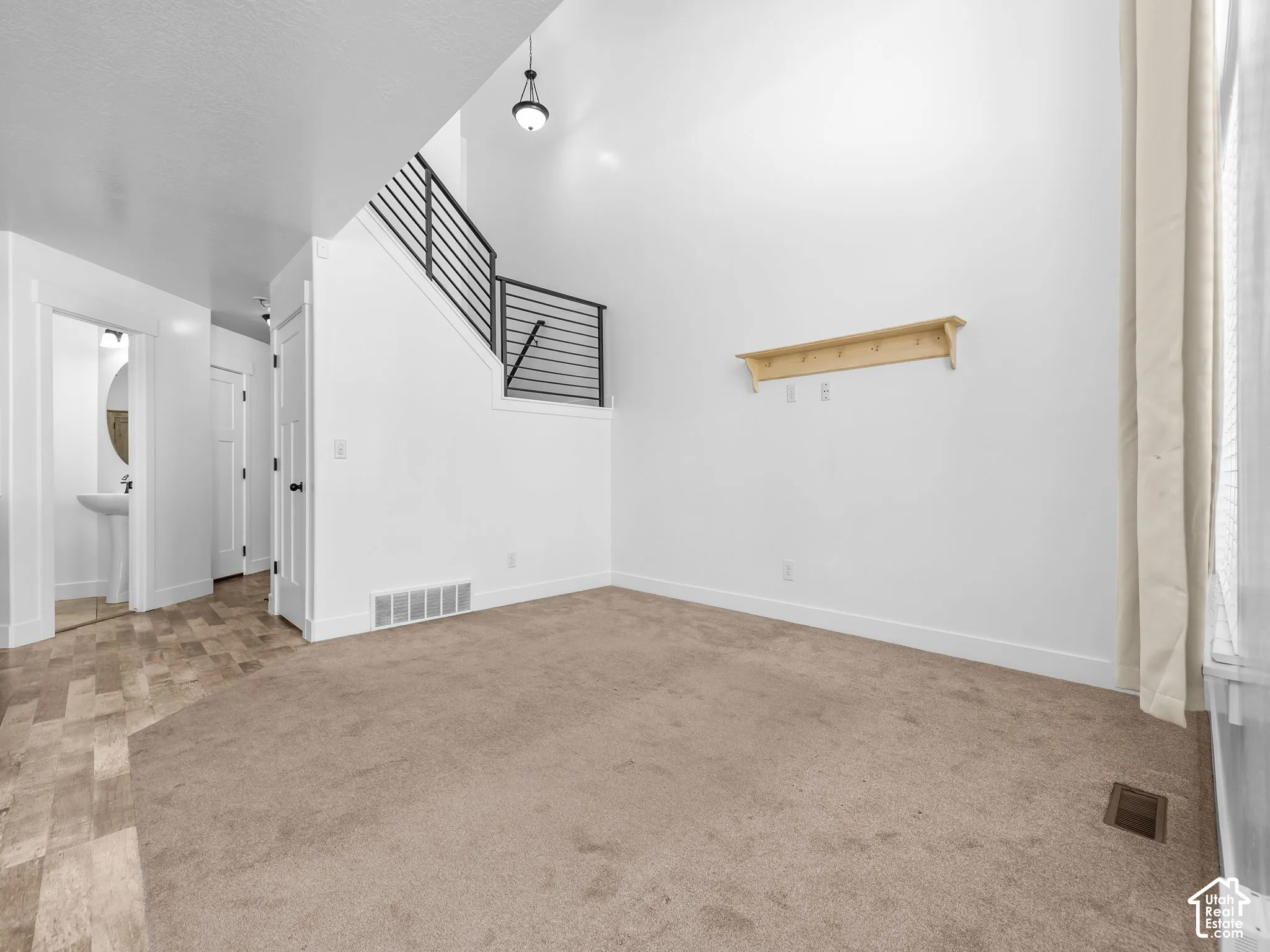 Vaulted ceiling with a pendant light fixture, carpeted flooring, and a contemporary stair railing
