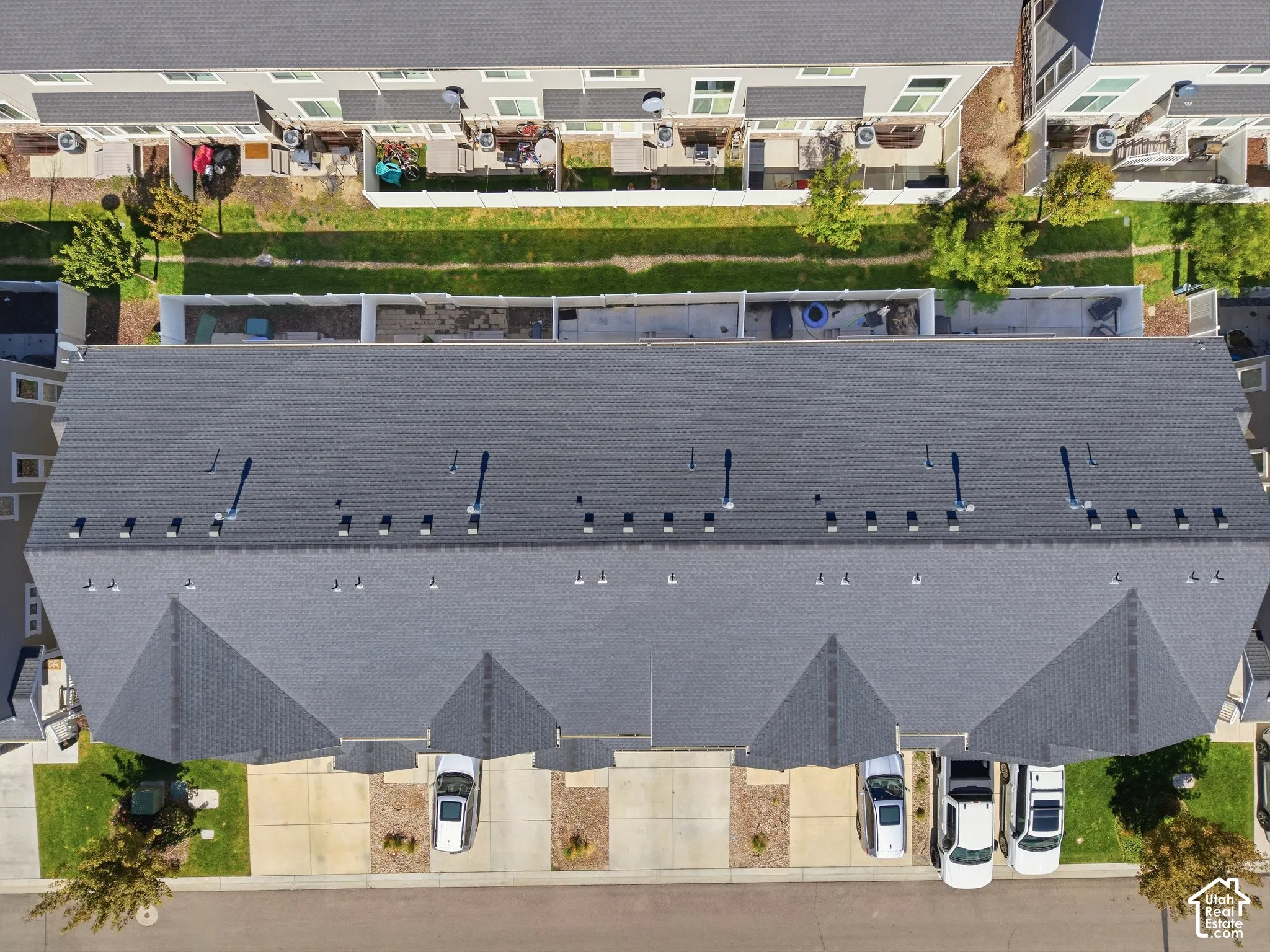 Gray shingle roofing with multiple ventilation fixtures, concrete driveways, and landscaped front yards