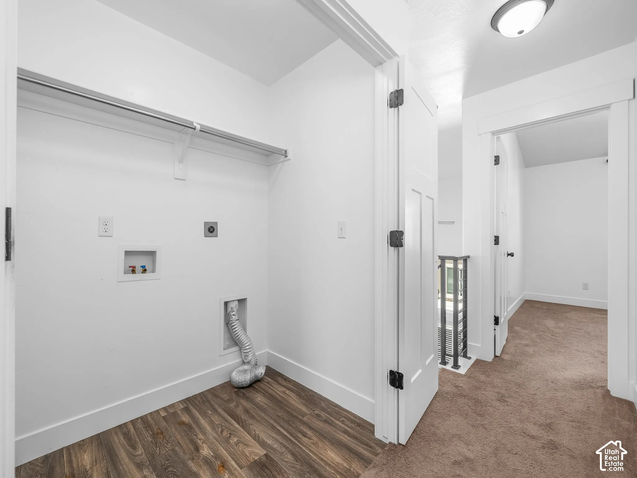 Dedicated laundry area with wood-finish flooring, featuring a clothes rod, and white walls