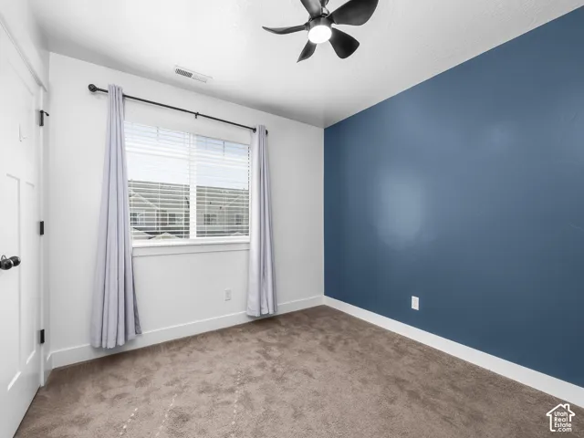 Carpeted room featuring a ceiling fan with integrated lighting, a window with blinds, and a paneled interior door