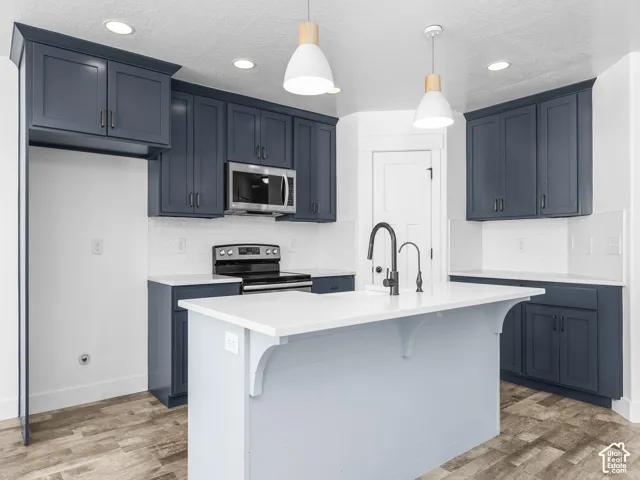 Kitchen featuring blue shaker-style cabinetry, white countertops, a white subway tile backsplash, and wood-finish flooring