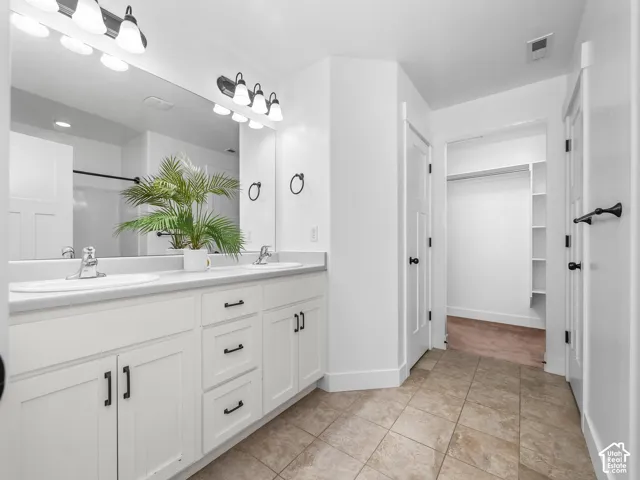 Dual sink vanity with white cabinetry and dark hardware