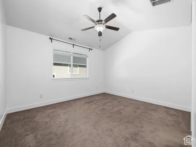 Vaulted ceiling, ceiling fan with light fixture, white walls, window with black curtain rod, carpeted flooring