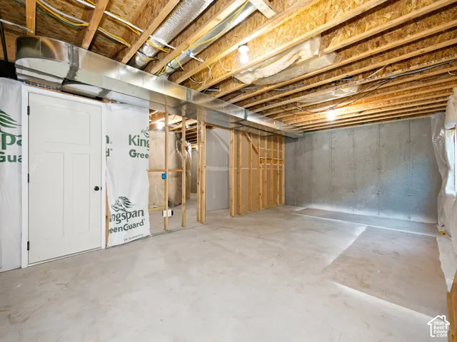 Unfinished basement featuring exposed wood joists, concrete flooring, concrete walls, and framed interior walls