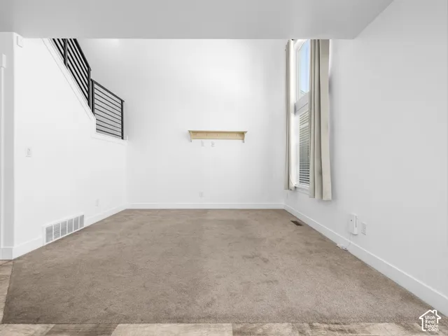 High ceilings, carpeted flooring, white walls, built-in shelving, and a modern horizontal railing staircase