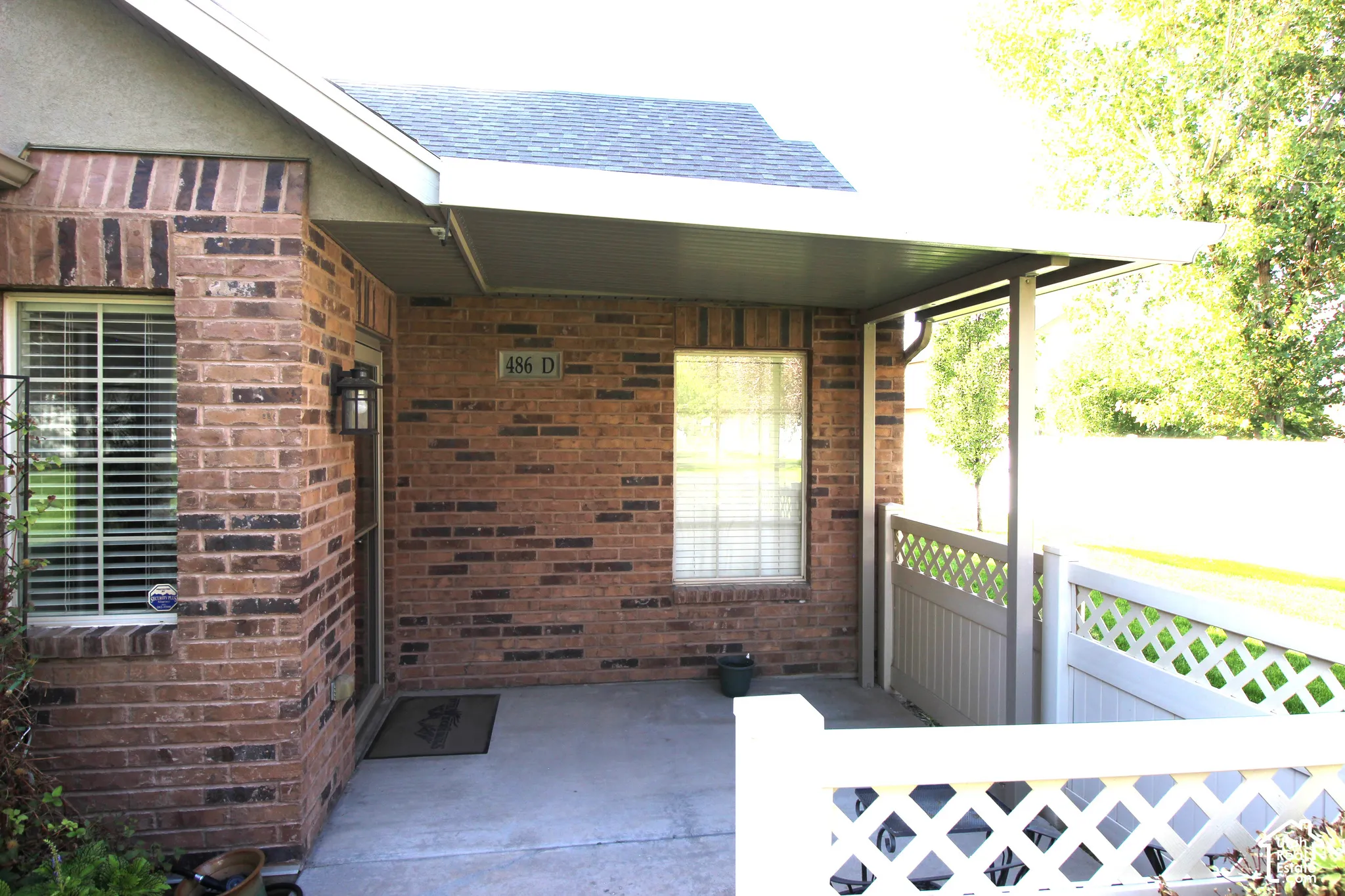 Brick exterior with contrasting trim, covered entry, lattice fencing, and exterior wall lantern