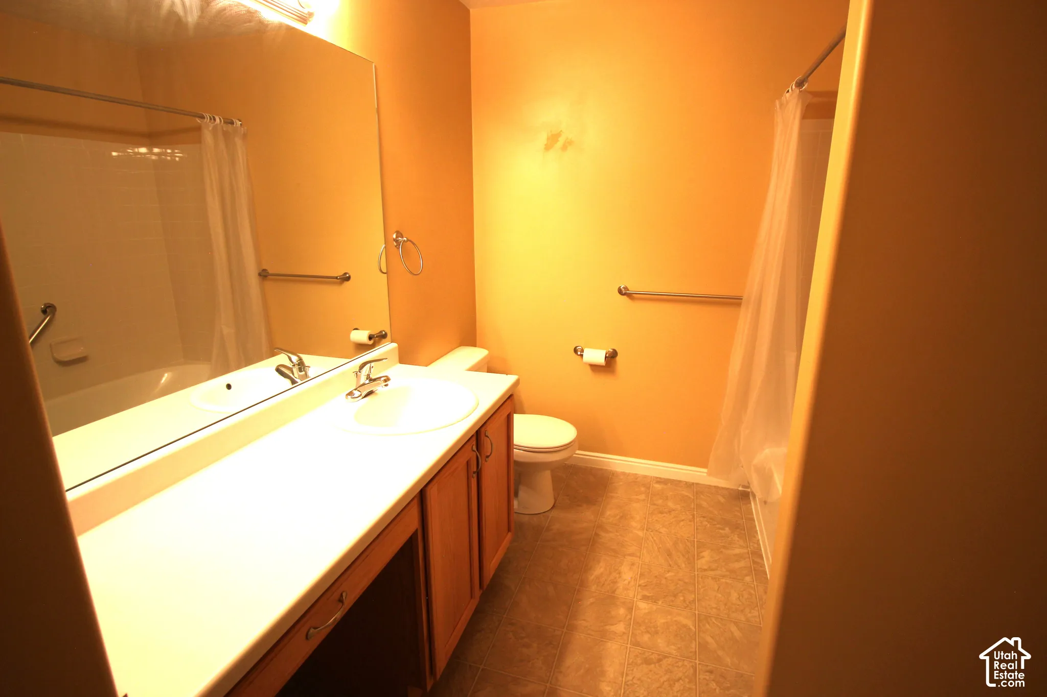 Hallway Bathroom with Full-width vanity with an integrated sink, wood-finish cabinetry, large wall-mounted mirror, and a shower-tub combination featuring a metal grab bar