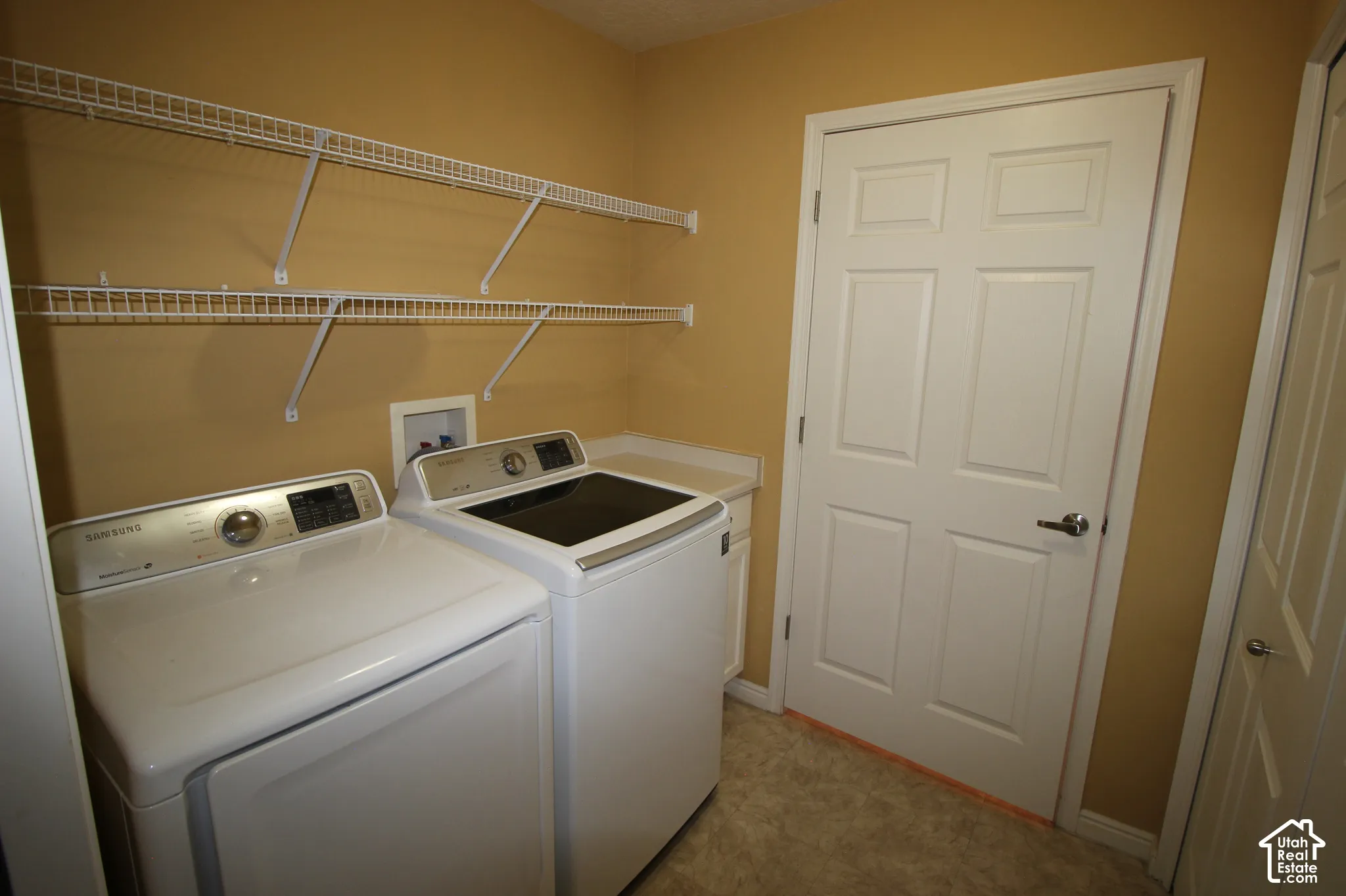 Laundry room featuring dual-level white wire shelving, a built-in cabinetry counter, and a six-panel door