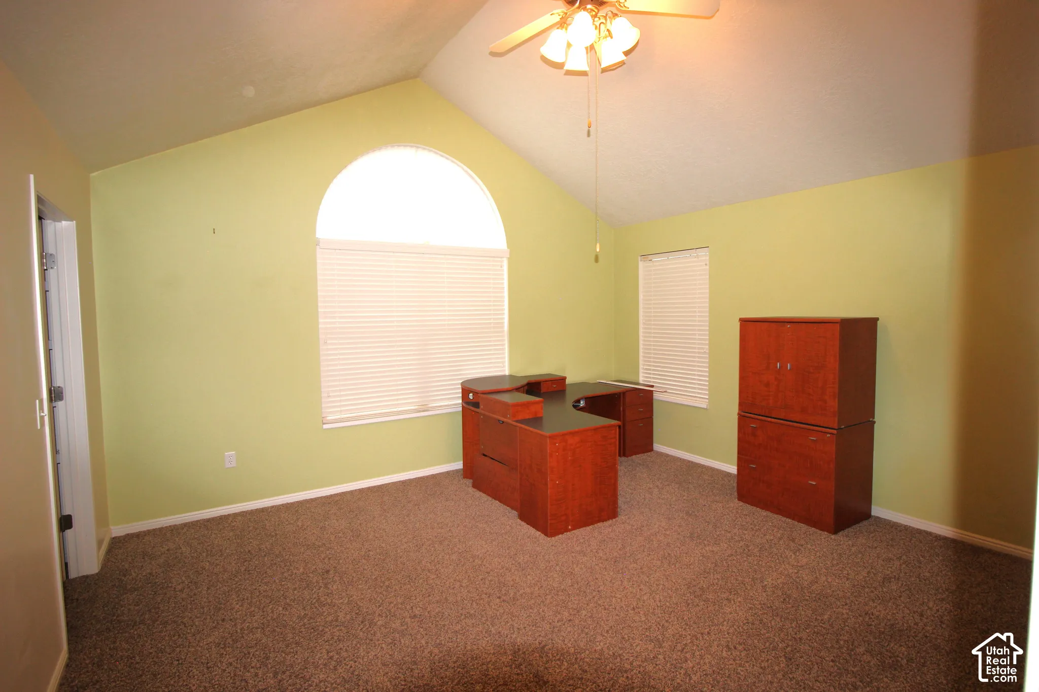 @nd bedroom or office with Vaulted ceiling, arched window, wall-to-wall carpeting, and ceiling fan with integrated lighting