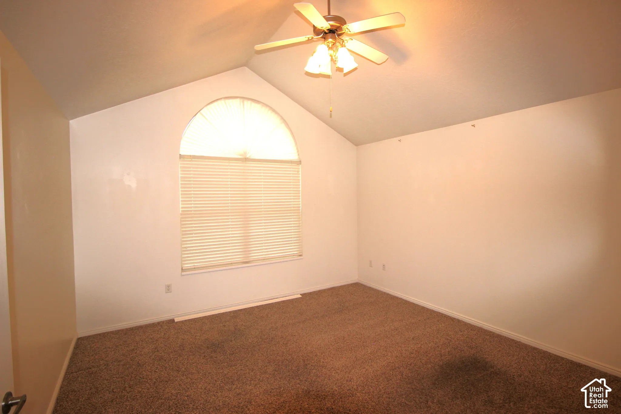 Master Bedroom with Vaulted ceilings featuring a central ceiling fan with integrated lighting and an arched window