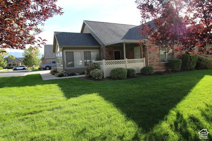 Brick exterior with a gabled roofline, covered porch, and lattice fencing