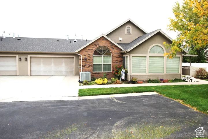 Exterior featuring a multi-car garage, mixed-material facade of brick and stucco, arched windows, and a paved driveway
