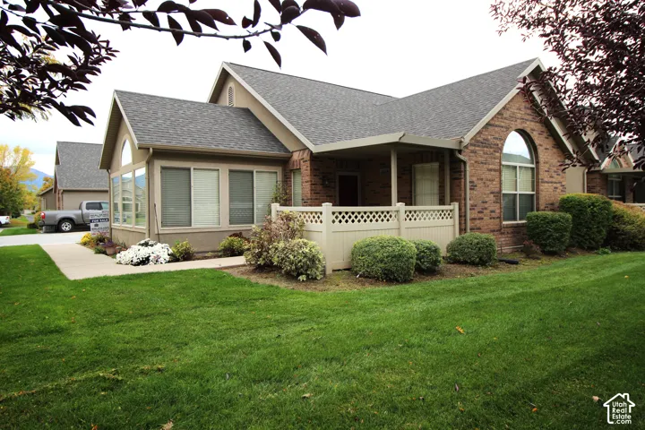 Exterior featuring a brick and stucco facade, an arched window, a covered porch with decorative latticework railing, and a concrete walkway