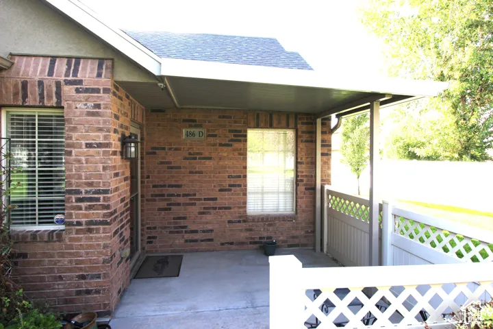 Brick exterior with contrasting trim, covered entry, lattice fencing, and exterior wall lantern