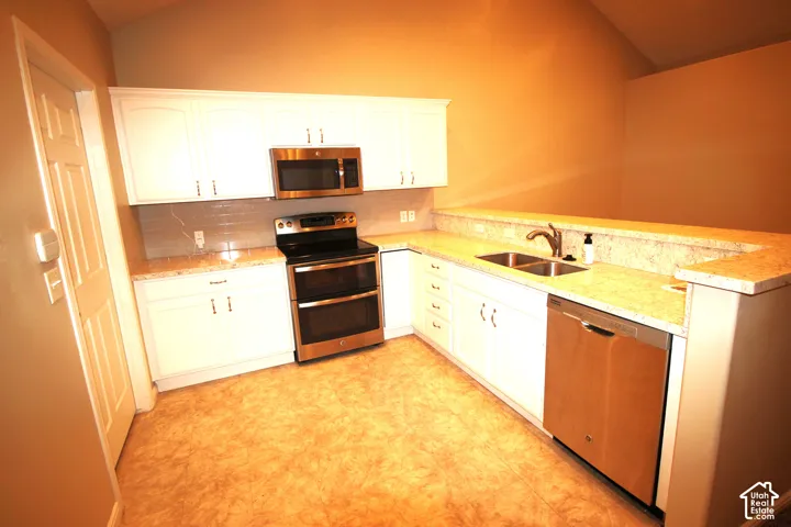 Kitchen featuring white cabinetry, stainless steel appliances, a double-Large Kitchen with basin sink, nice  countertops, and vaulted ceilings