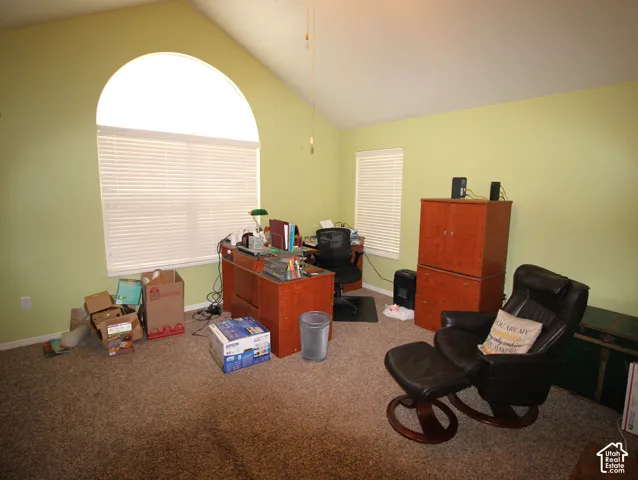 Vaulted ceiling featuring an arched window, additional window, and light carpet flooring