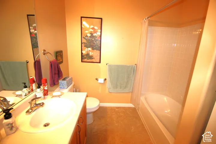 Bathroom featuring a vanity with an integrated sink, a large wall-mounted mirror, a toilet, and a combined bathtub and shower with white tile surround