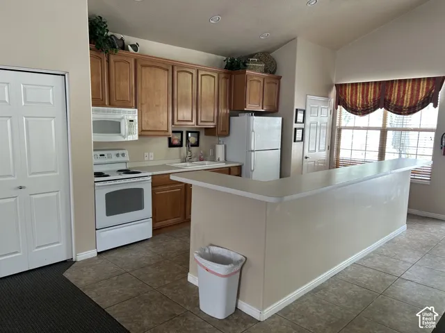 Club House - Kitchen featuring wood-finish cabinetry, white appliances, recessed lighting, and a breakfast bar