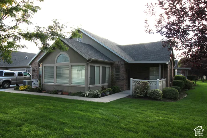 Stucco and brick exterior with a gabled roofline, arched window, and established landscaping