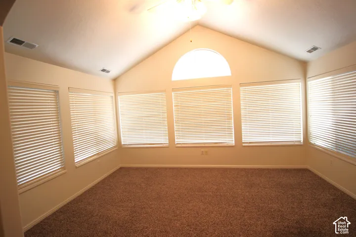 Large Sunroom - Vaulted ceiling, arched window, multiple windows with blinds, neutral wall coloring, and wall-to-wall carpeting