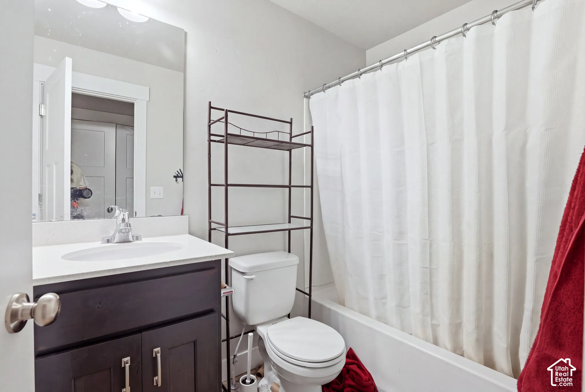 Vanity with a white countertop and integrated sink, chrome faucet, and dark wood-finish cabinetry