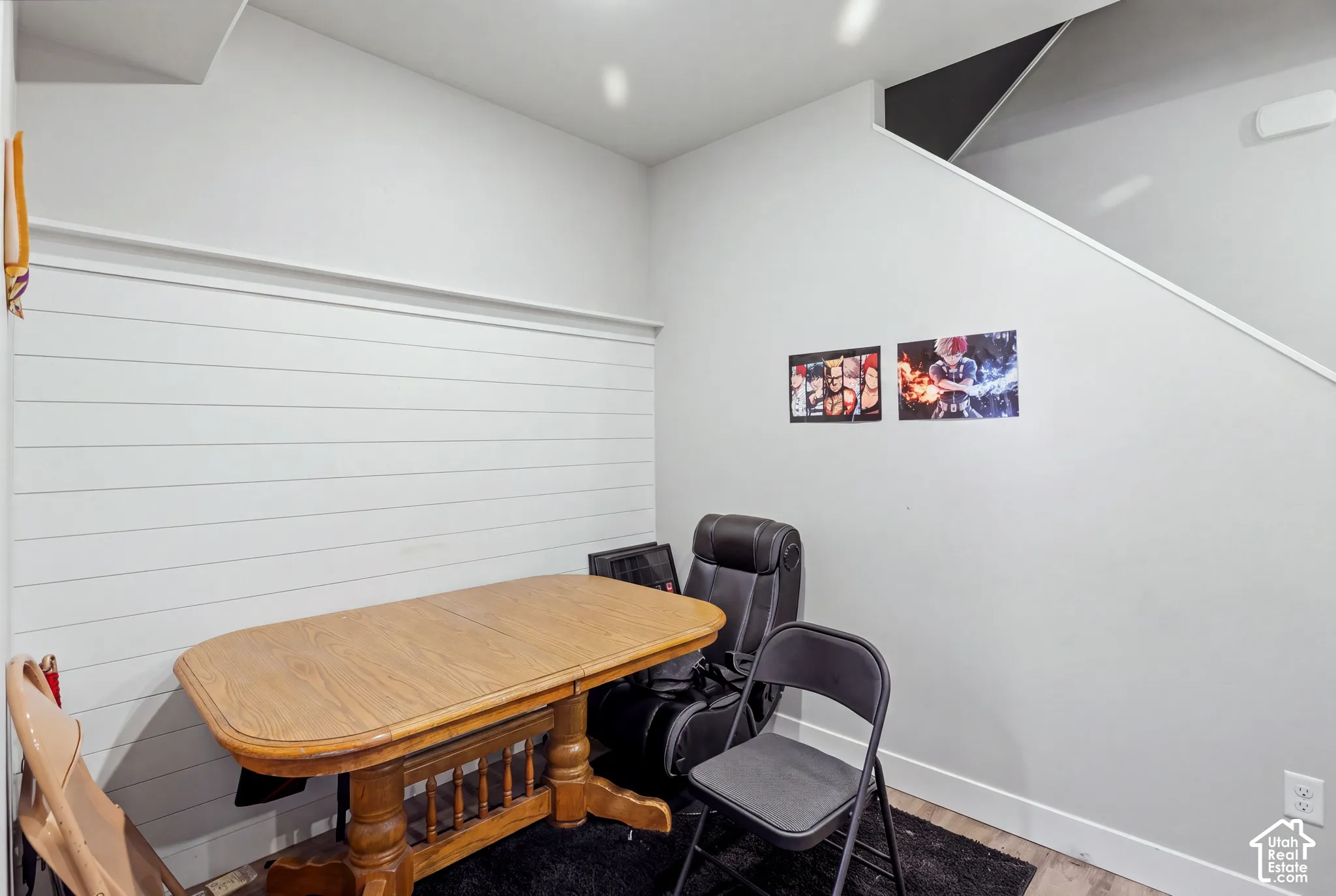 White shiplap accent wall, light-toned wood-finish flooring, and a staircase with a dark underside