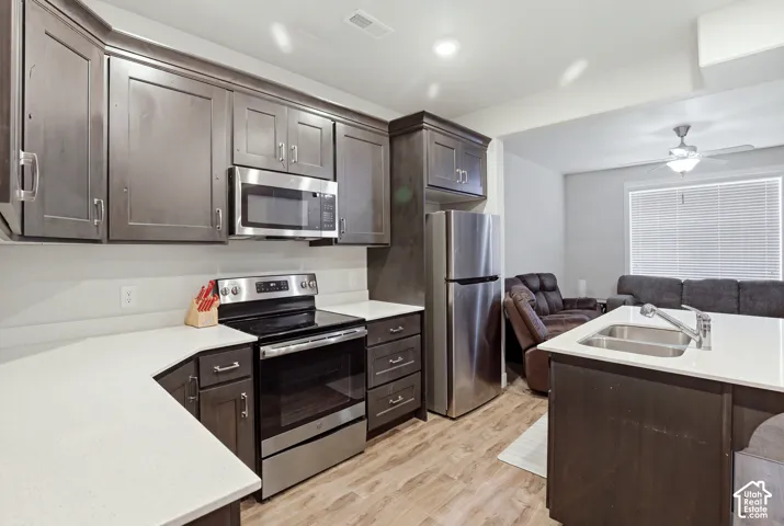 Kitchen featuring stainless steel appliances, dark wood-finish cabinetry, white countertops, and wood-finish flooring