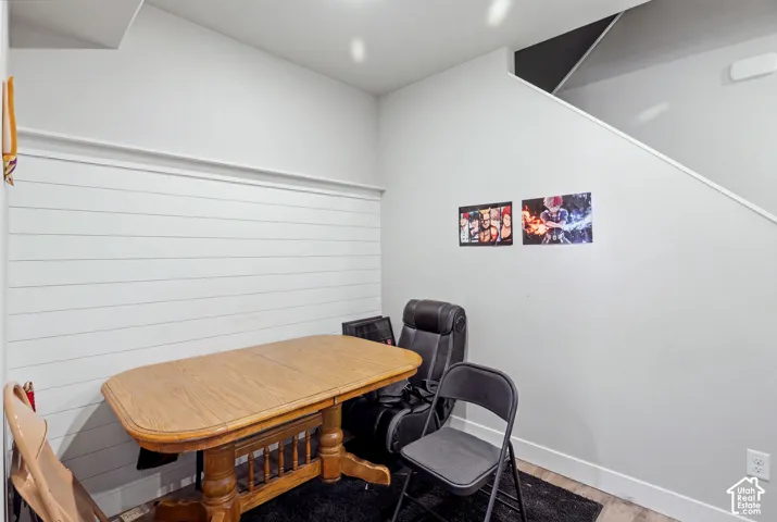 White shiplap accent wall, light-toned wood-finish flooring, and a staircase with a dark underside
