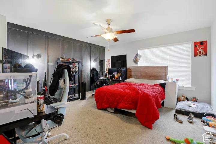 Wall-mounted sconce lighting, ceiling fan with integrated light, window with blinds, and light-toned carpeting