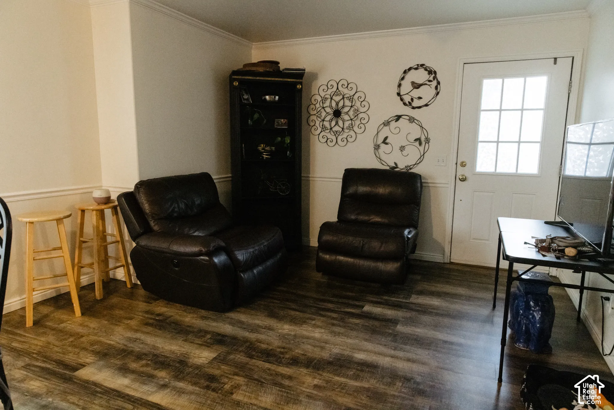 Wood-finish flooring with white baseboards and crown molding