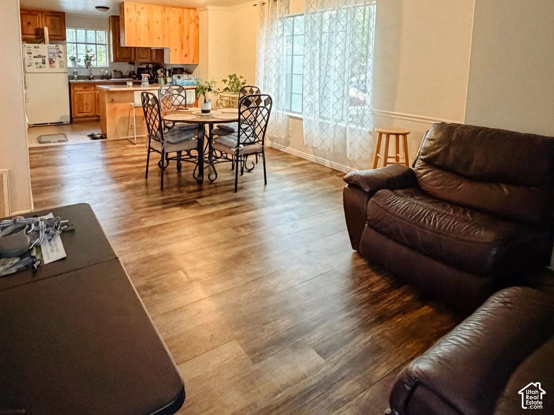 Wood-finish flooring throughout, with a dining area featuring a round table and wrought iron chairs
