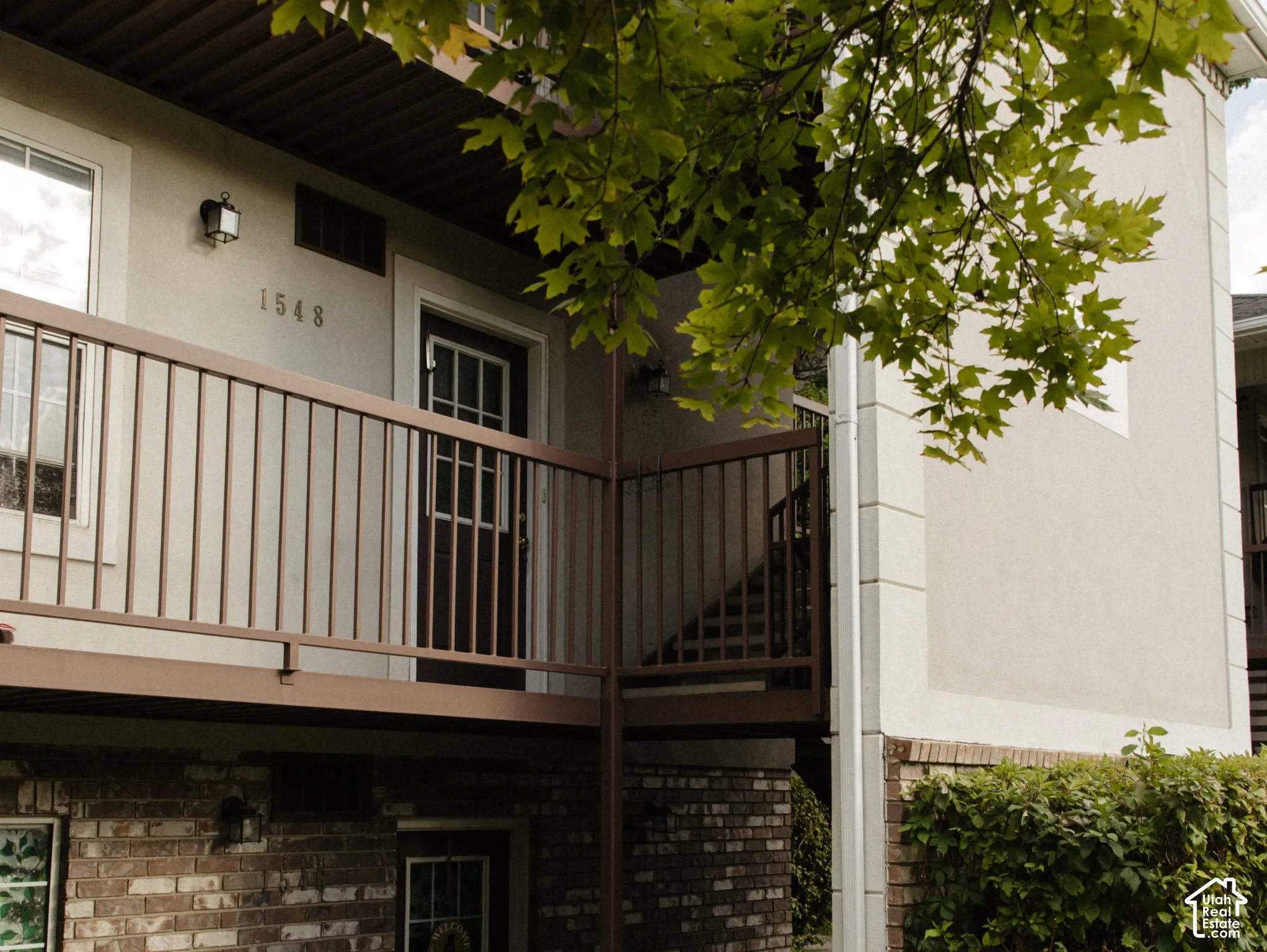 Exterior featuring a brick facade, stucco siding, and a concrete walkway