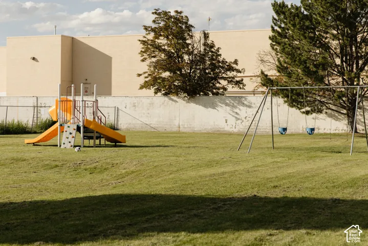 Expansive green space featuring playground equipment including a slide and swing set