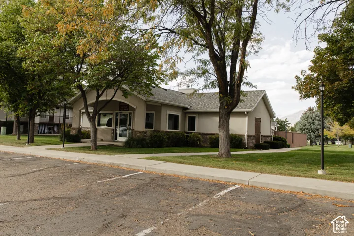 Stucco exterior with stone veneer accents, gabled shingle roof, and established landscaping