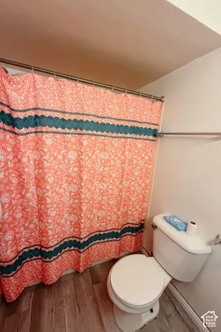 Wood-finish flooring with a white toilet and a built-in towel bar
