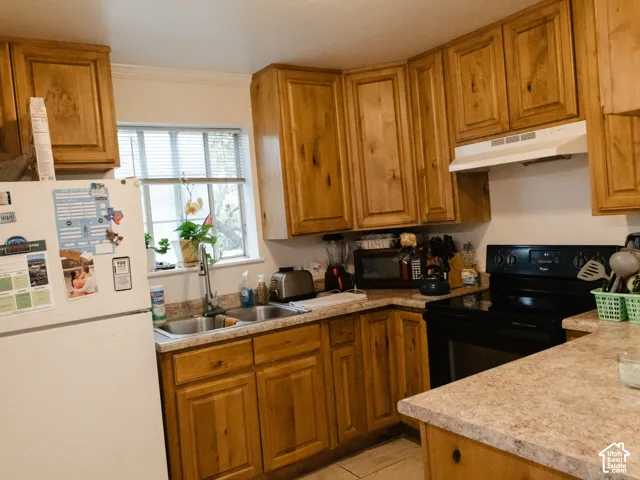Kitchen featuring wood-finish cabinetry, a double basin sink, and a black range