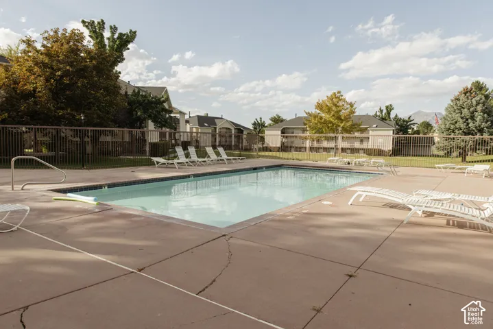 Community pool with surrounding concrete decking, metal handrails, and a perimeter fence