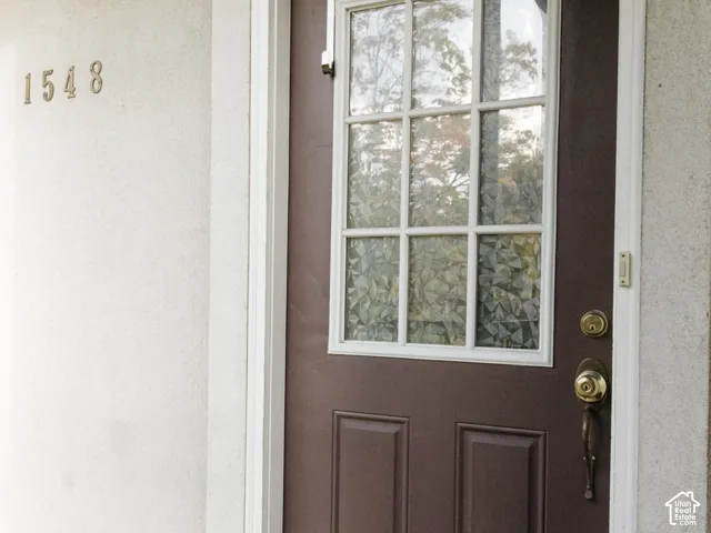 Brown front door with upper glass panel featuring gridded muntins, brass hardware, and white trim