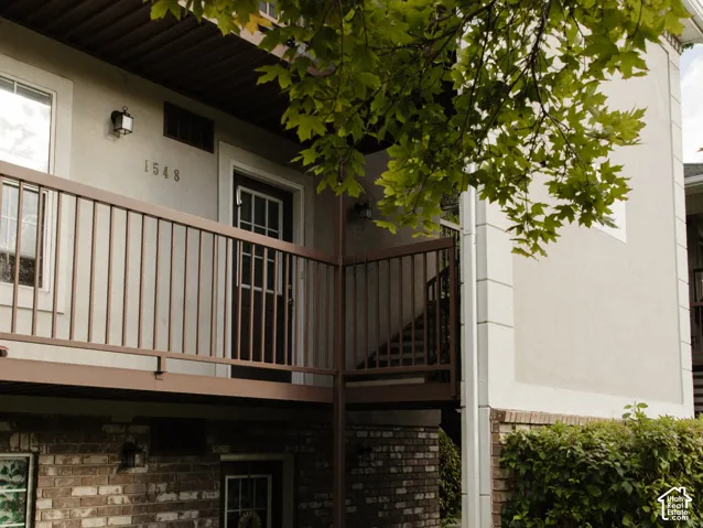 Exterior featuring a brick facade, stucco siding, and a concrete walkway