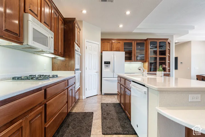 Kitchen featuring wood cabinetry, white appliances, recessed lighting, a built-in microwave, and an integrated kitchen island