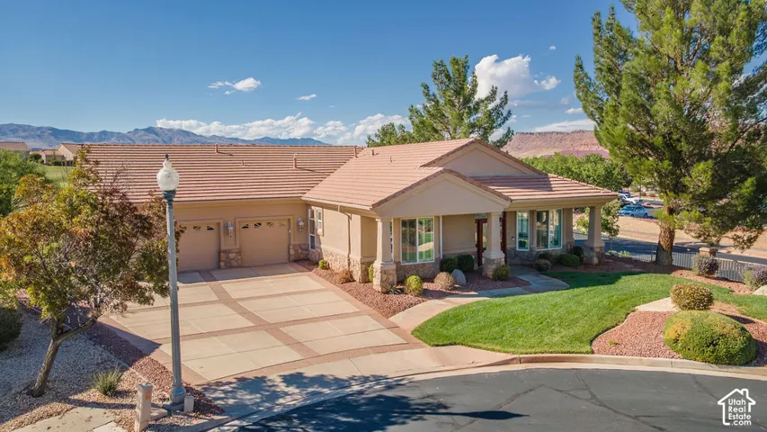 Mediterranean-style exterior with a tile roof, an integrated multi-car garage, and a paver driveway