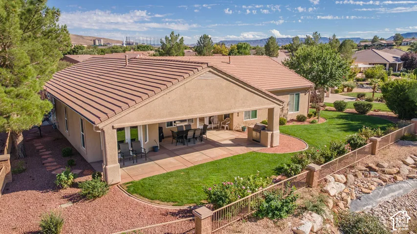 Expansive patio with a partial overhang, stone pavers, and a built-in outdoor grill