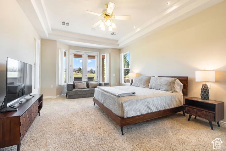 Tray ceiling with recessed lighting and a ceiling fan, plush carpet flooring, and a bay window with exterior access