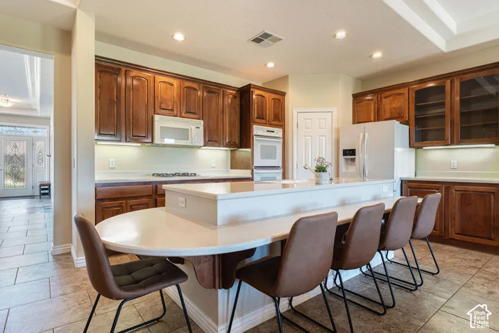 Spacious kitchen featuring extensive wood cabinetry, white countertops, built-in microwave, and a large central island with seating