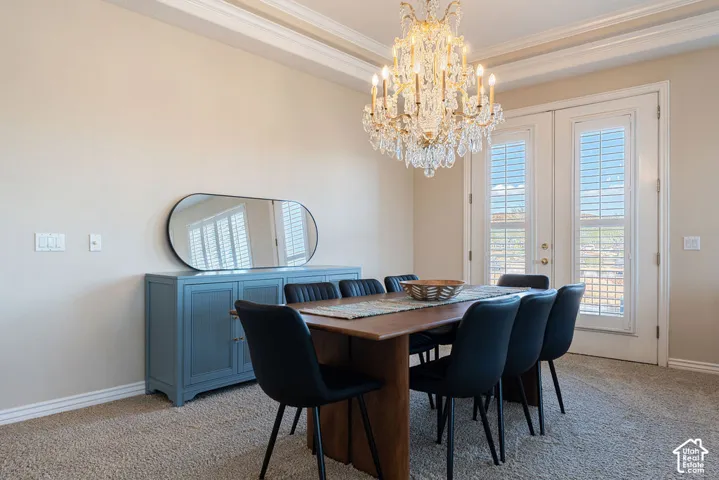 Tray ceiling with crown molding, crystal chandelier, and French doors with plantation shutters