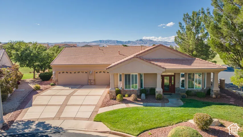 Stucco exterior with a tiled roof, multi-car garage, and a patterned concrete driveway
