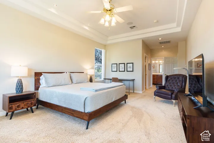 Tray ceiling with recessed lighting and a ceiling fan, carpet flooring, and a large window