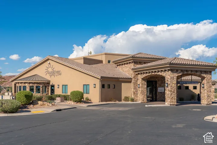 Stucco and stone exterior with arched entryway and multiple windows, featuring a tiled roof and landscaped surroundings