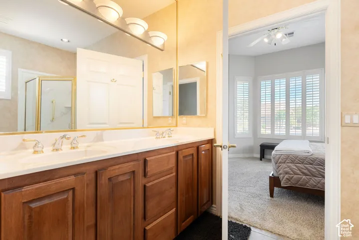Dual vanity with wood-finish cabinetry, white countertop, and gold-finish fixtures